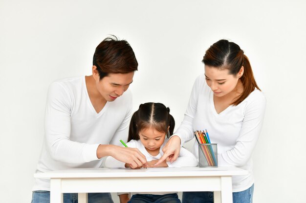 사진 바탕 에 앉아 있는 부모 와 함께 책상 에서 종이 에 그림 을 그리는 소녀