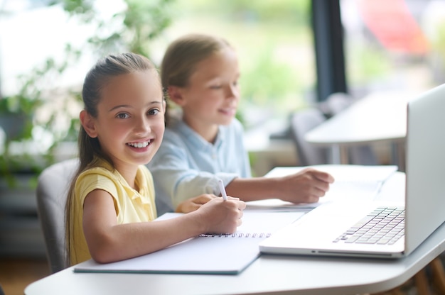 Girl with a pen and her classmate sitting at the desk