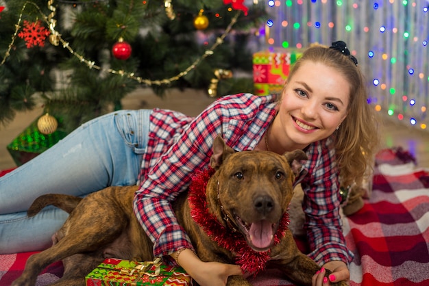 A girl with a pet dog under a Christmas tree