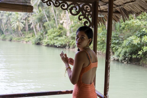 Girl with the phone in a boat in the river