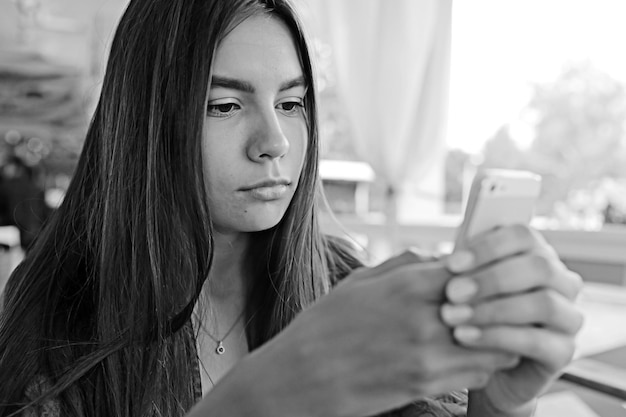 Photo girl with a phone in a cafe in the summer