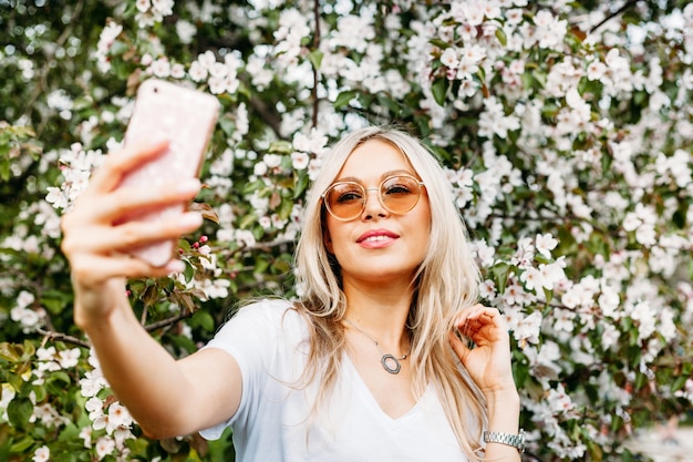 Photo a girl with a phone in her hand takes pictures of herself, selfies