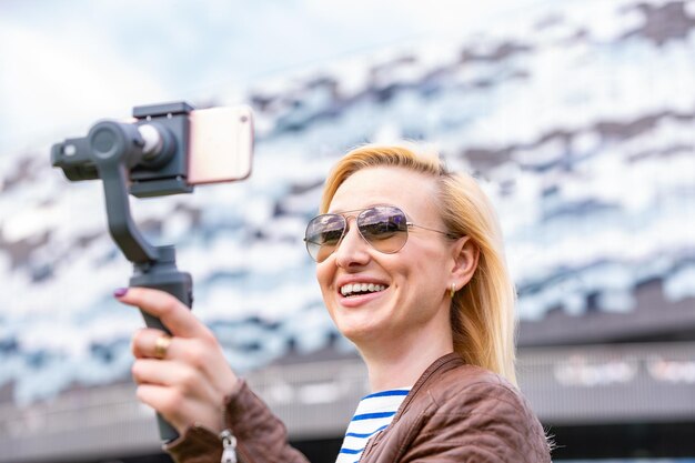 The girl with the phone on the stabilizer leads the videoblog She takes herself to the camera Smartphone