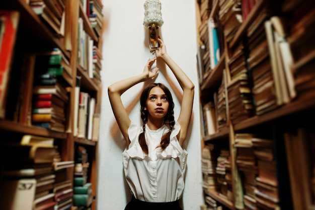 Girl with pigtails in white blouse at old library