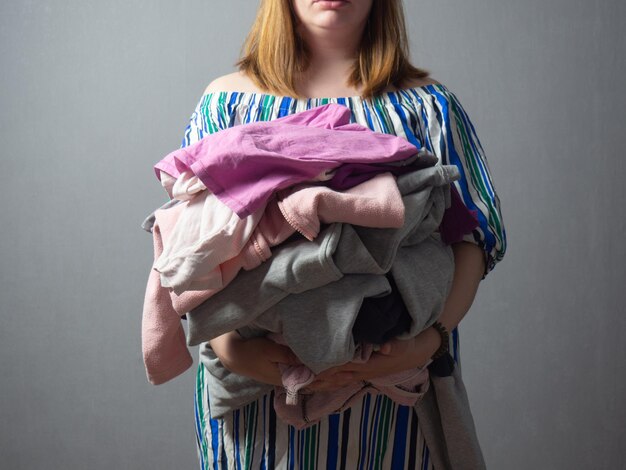 Girl with a pile of laundry on a gray background