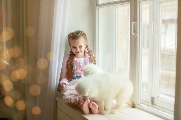 La ragazza con un cuscino e un cucciolo bianco tra le braccia.