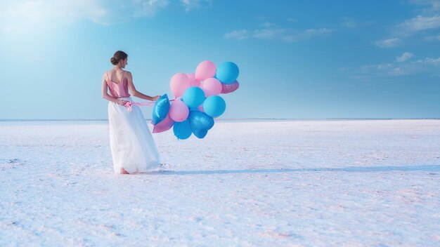 Girl with pink blue balloons on a salt lake