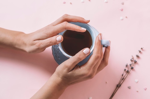 Foto ragazza con la tazza di tè rosa della holding del manicure