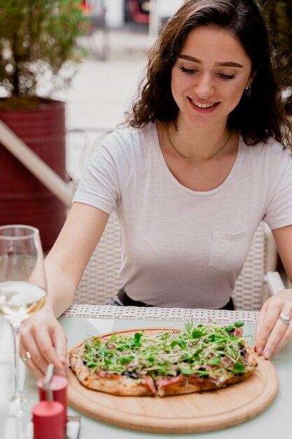 Girl with pinsa romana in cafe on summer terrace. Young woman eating pinsa and drinking wine.