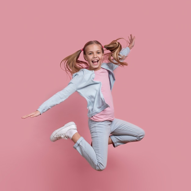 Girl with pony tails jumping and smiles