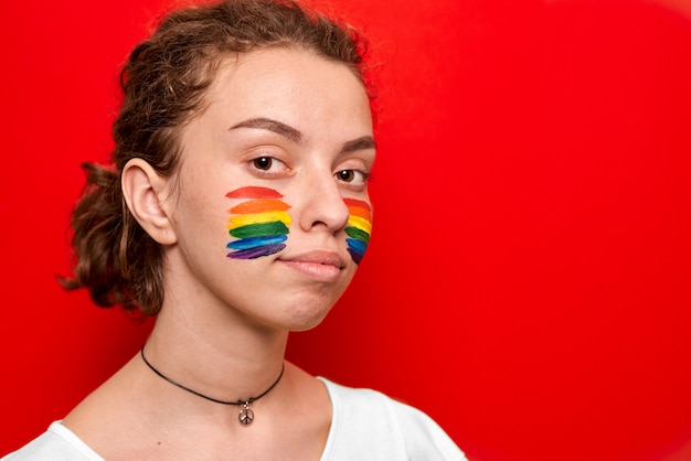 Girl with pride flag painted on her cheeks smiling