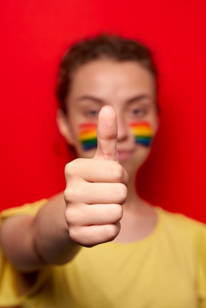 Photo girl with pride flag painted on her cheeks smiling