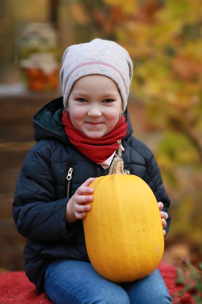 写真 秋の公園でカボチャを持つ少女