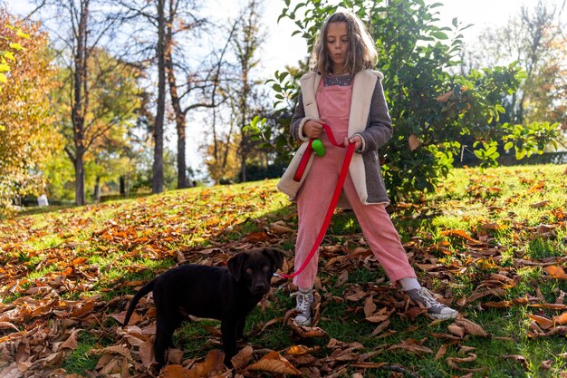 Girl with puppy on lawn in autumn park