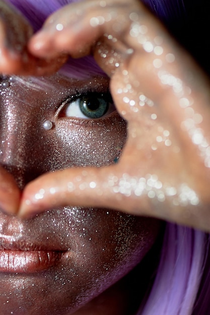 Una ragazza con i capelli viola e la pelle luminosa un alieno o una fata con la pelle luminosa le sue mani sono piegate davanti al viso a forma di cuore