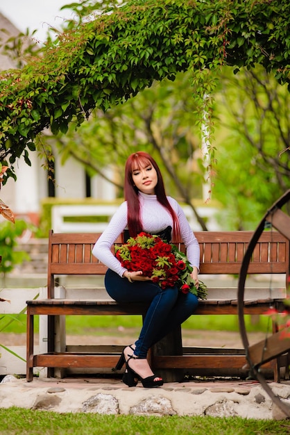 Girl with red hair holding red roses in her hands