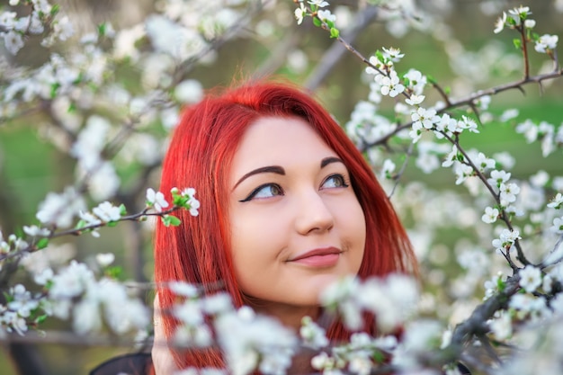 赤い髪の少女が木の花の香りを吸い込む