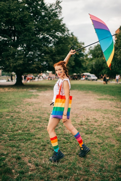 Girl with red hair and lgbt flag on her face, colorful mismatched socks