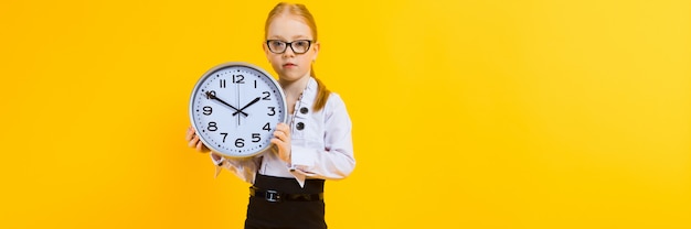 Girl with red hair on a yellow A charming girl in transparent glasses is holding a watch