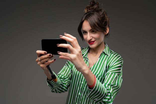 girl with red lipstick on her lips makes selfie on a dark wall