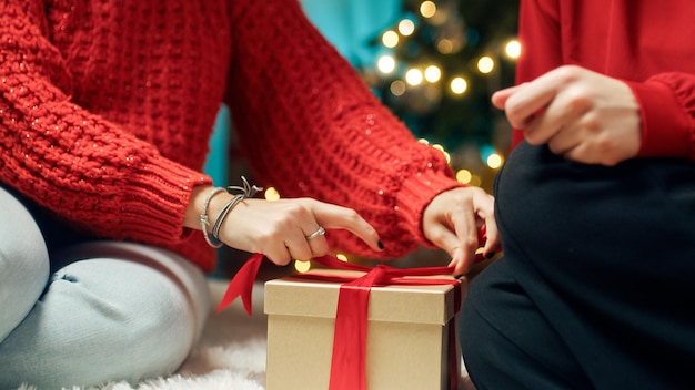 写真 赤いセーターの女の子がクリスマス プレゼントを準備します。