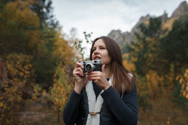 Ragazza con la retro macchina fotografica nelle montagne di autunno