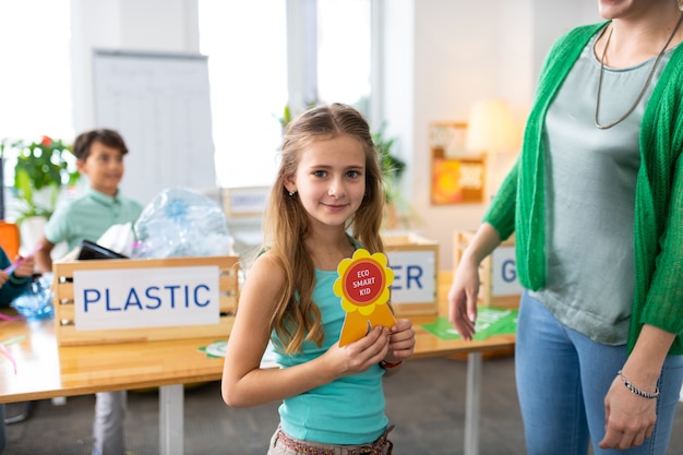 Girl with reward. Cute schoolgirl feeling happy after receiving reward for being eco friendly