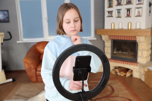 Girl with a ring lamp for a smartphone distance education