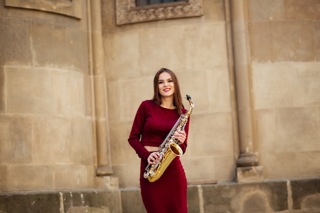 Girl with saxophone playing on street