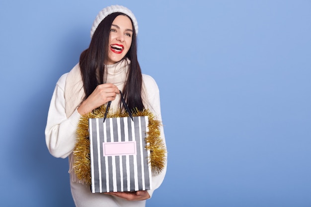 Girl with shopping bag posing isolated over blue space