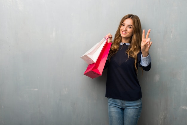 Girl with shopping bags smiling and showing victory sign