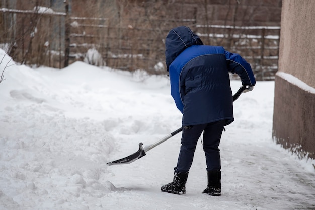 Girl with a shovel cleans snow in the yard. High quality photo