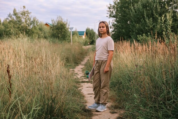 Girl with skateboard on path in park