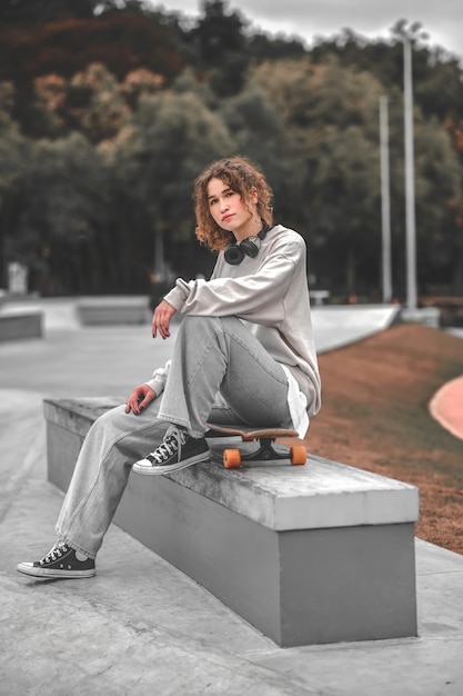 Girl with skateboard sitting in park