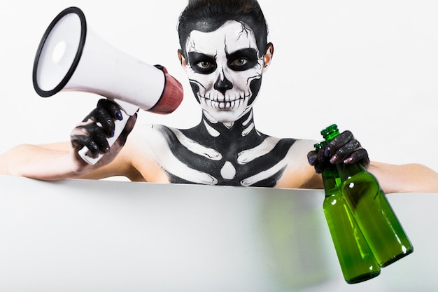 Girl with skeleton makeup hold bottle and megaphone