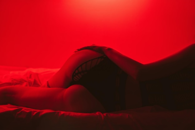 Ragazza con un corpo snello e culo sexy in bella biancheria intima giace eroticamente sul letto