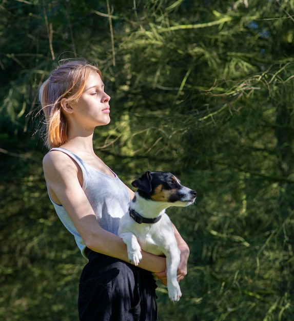 Girl with a small Jack Russell dog in her arms in nature