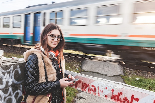 通過する電車を持つスマートフォンを持つ少女。