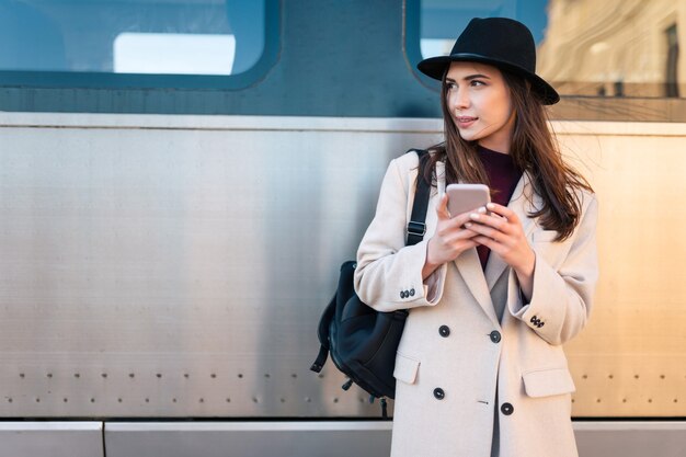 電車の近くでスマートフォンを持つ少女