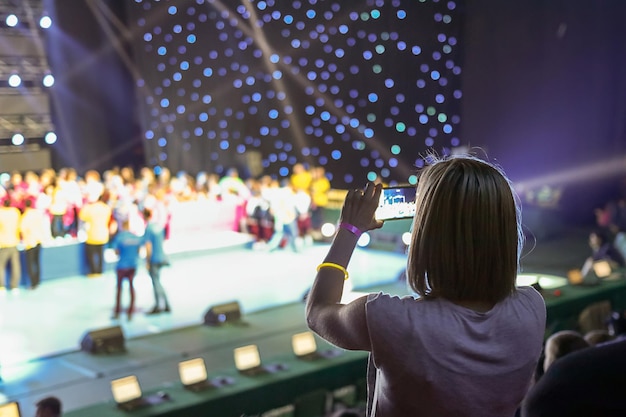 Photo girl with a smartphone taking photo of concert stage