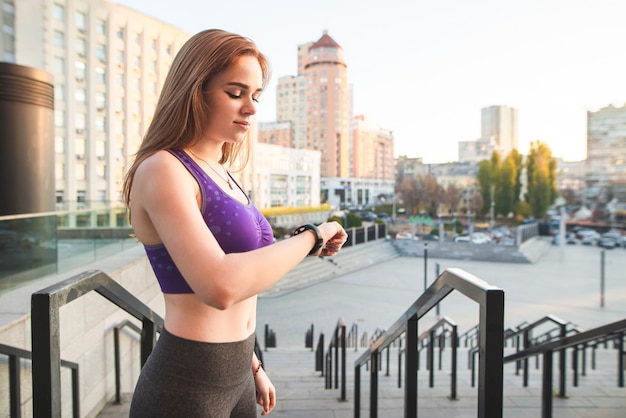 Девушка со спортивной фигурой стоит на фоне городского пейзажа