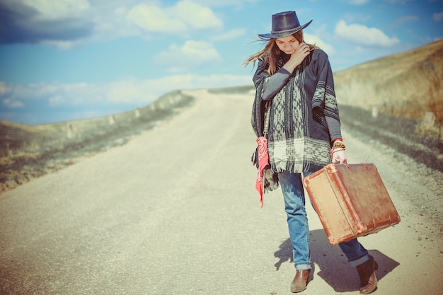 Girl with a suitcase on the road