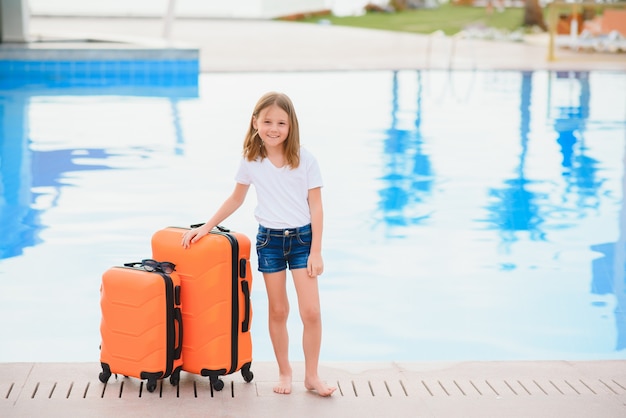 Girl with suitcases by the pool in a luxury hotel.