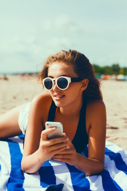 Ragazza con gli occhiali da sole e un telefono cellulare in mano