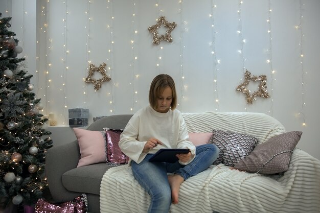 A girl with a tablet sits on the couch