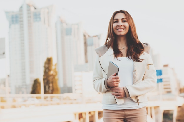 Girl with tablet with buildings on background.