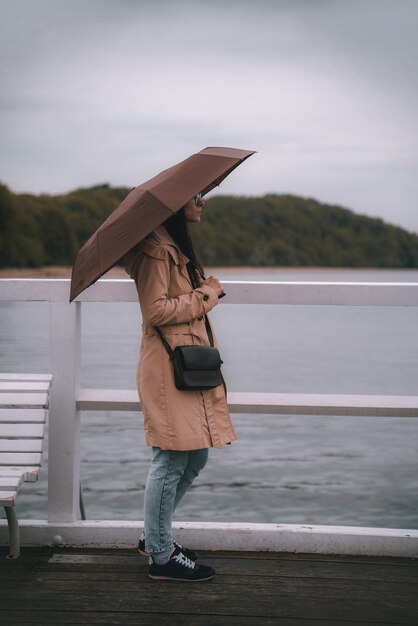 悪天候時の海での休暇に傘を持つ少女