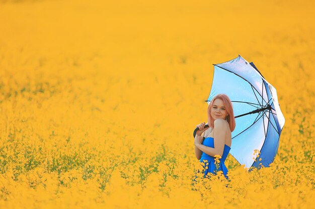 Girl with an umbrella in a summer field of flowers, country female nature yellow field