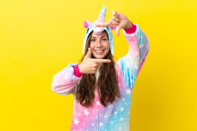 Girl with unicorn pajamas over isolated background focusing face. Framing symbol