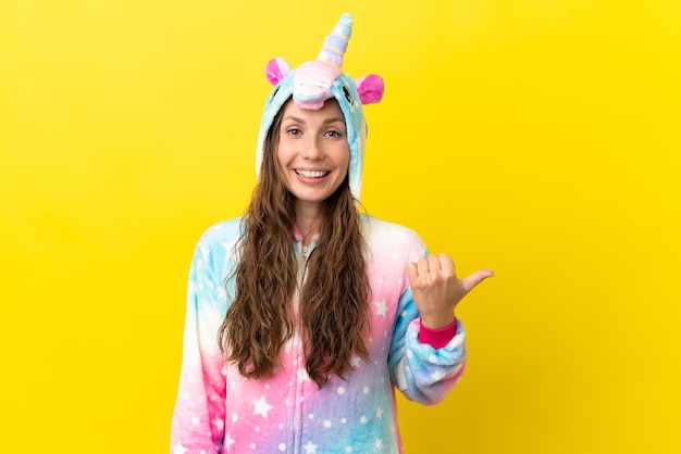 Girl with unicorn pajamas over isolated background pointing to the side to present a product